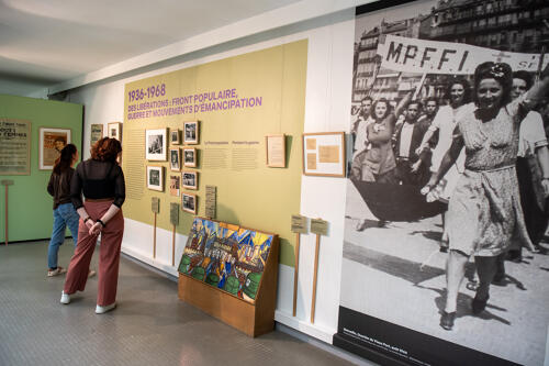 Visiteuses dans la partie 1936-1968 de l'exposition Les femmes sont dans la rue. Au premier plan un grand format d'une manifestation des francs tireurs partisants de Marseille menée par une femme